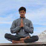 man meditating on brown wooden platform during daytime